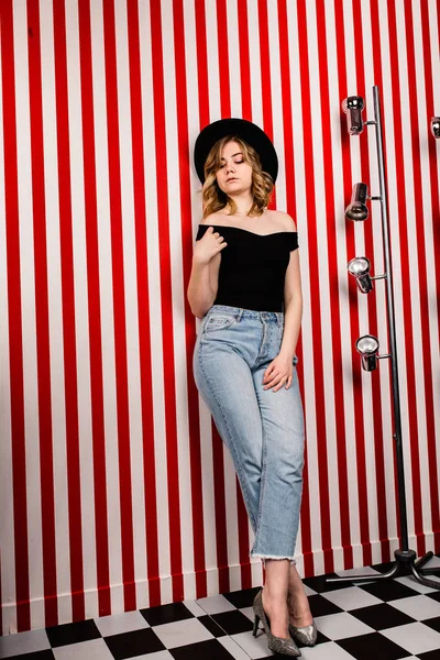 Stüdyoda poz veren şapkalı güzel bir kadın.