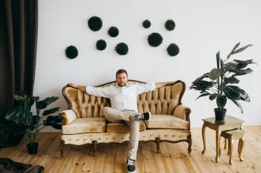 evde koltukta oturan genç yakışıklı adam