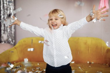 Mutlu şirin çocuk konfetilerle eğleniyor.