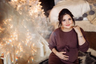 Mutlu güzel hamile kadın evde poz veriyor.