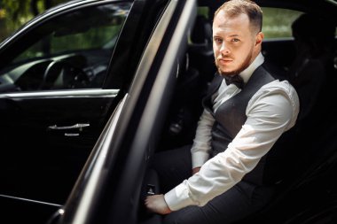 Arabayla poz veren yakışıklı, mutlu bir adam.