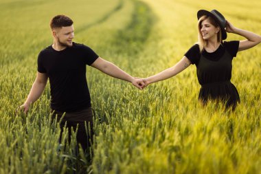 Güzel genç çift buğday tarlasında yürüyor