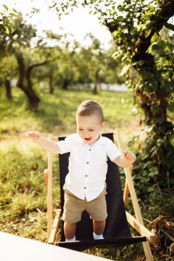 Parktaki sandalyede dinlenen mutlu çocuk.