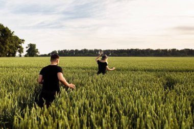Güzel genç çift buğday tarlasında yürüyor