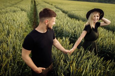 Güzel genç çift buğday tarlasında yürüyor