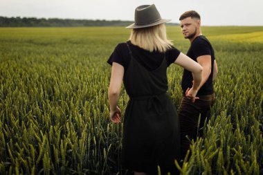 Güzel genç çift buğday tarlasında yürüyor