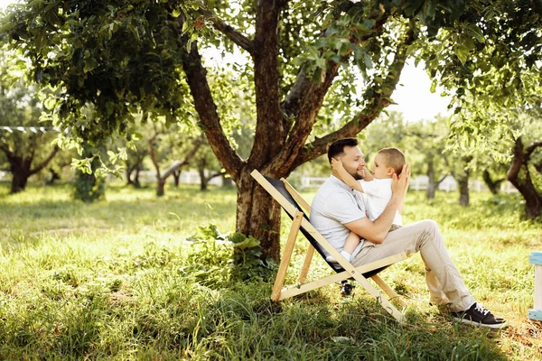椅子の上の公園で息子と幸せな若い父親 — ストック写真