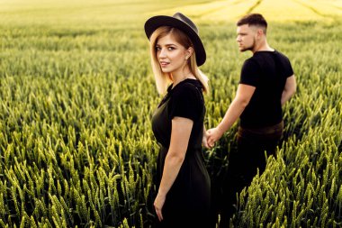 Güzel genç çift buğday tarlasında yürüyor