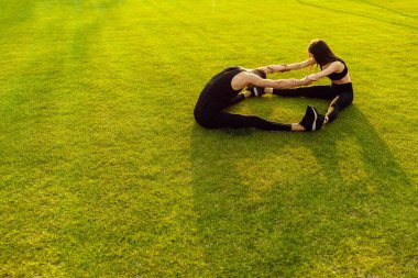 Genç sporcular parkta egzersiz yapıyor.