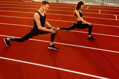 Genç adam ve kadın stadyumda egzersiz yapıyorlar.