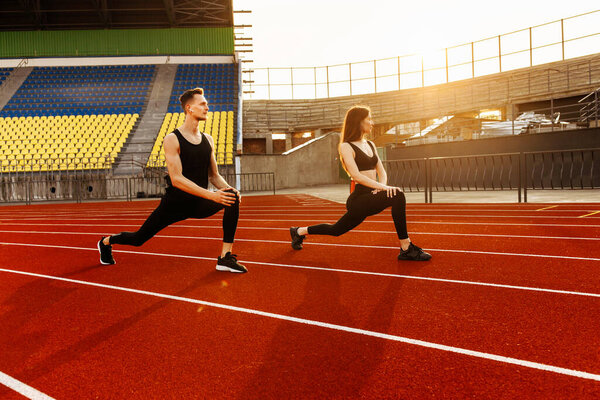 young man and woman exercising on the stadium