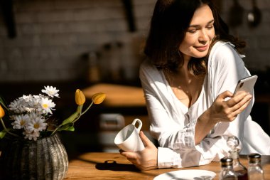 Mutfakta akıllı telefonu olan bir kadın. 