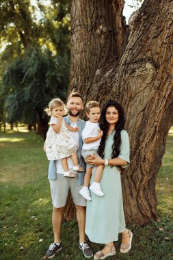 Parkta dinlenen çocuklu mutlu bir aile.