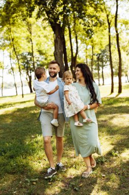 Parkta dinlenen çocuklu mutlu bir aile.