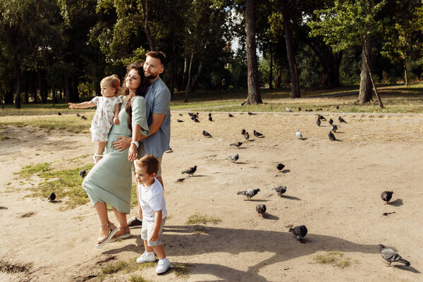 Happy young family with children relaxing  in the park by pond