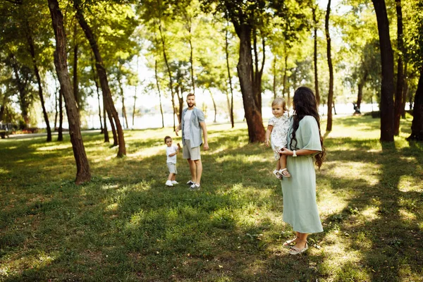 公園でリラックスしている子供たちと幸せな若い家族 — ストック写真