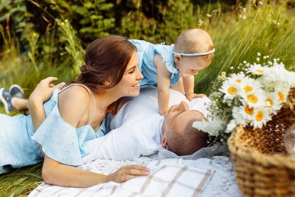 庭でピクニックをしている赤ちゃんを持つ美しいカップル — ストック写真
