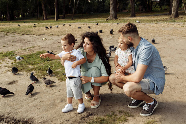 Happy young family with children relaxing  in the park by pond