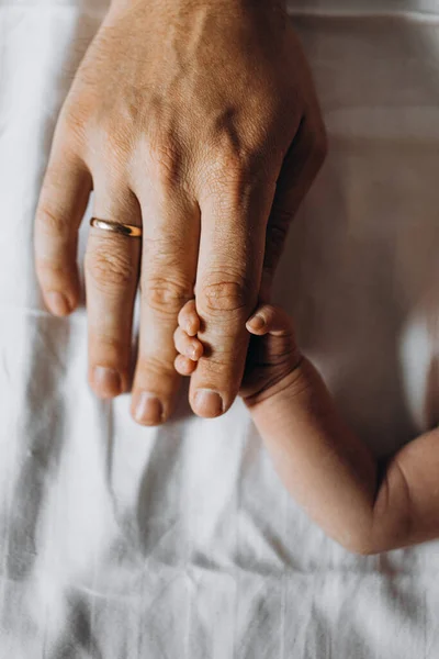 Portret van kleine hand van schattige pasgeboren baby meisje houden een ouder vinger, gelukkig gezin genieten van tedere momenten, geboorte en ouderschap concept — Stockfoto