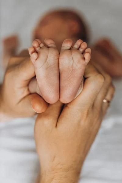 Portret van mooie kleine benen met kleine vingers, van schattig pasgeboren baby meisje, in zorgzame ouder armen, gelukkige familie momenten, geboorte en kindertijd concept — Stockfoto