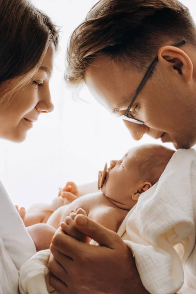 Beautiful parents with newborn baby, loving mom hold little daughter in arms, caring dad gently hold a hand of adorable baby girl, enjoy tender family moments, parenting concept — Stock Photo, Image