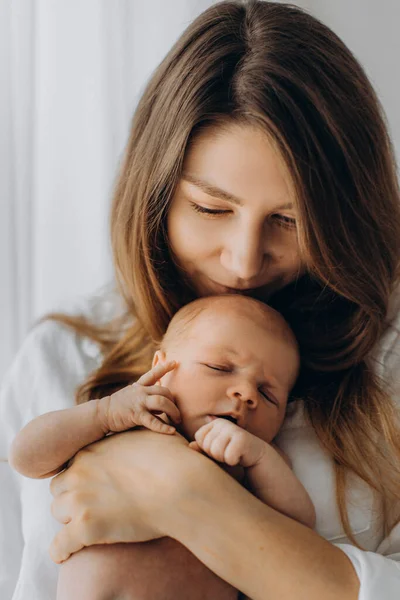 Великолепная женщина держит новорожденную девочку на руках, счастливая мама наслаждается нежными моментами прощания с маленькой дочкой, материнством — стоковое фото