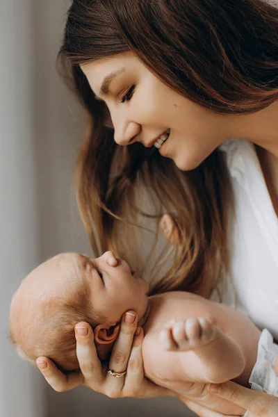 Wanita muda yang gembira memegang bayi perempuan yang baru lahir dalam pelukan, ibu yang peduli melihat dengan cinta pada anak kecil, tersenyum, menikmati kebahagiaan orangtua, konsep persalinan — Stok Foto