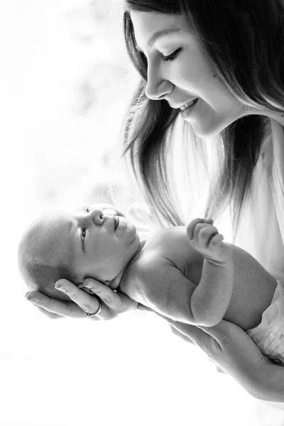 Сверхрадостная молодая женщина держит новорожденную девочку на руках, заботливая мать смотрит с любовью на маленькую дочь, улыбаясь, наслаждаться счастьем воспитания, концепция материнства — стоковое фото