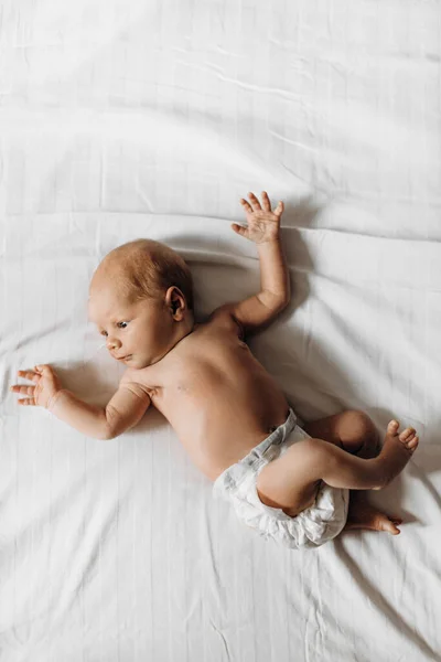 Preciosa niña recién nacida acostada en la cama, pequeña mirada humana a su alrededor con gran interés, conocer un mundo, nacimiento y concepto de la infancia — Foto de Stock