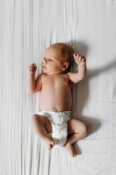 Linda menina recém-nascida deitada na cama, olhar pouco humano ao redor com grande interesse, conhecer um mundo, conceito de nascimento e infância — Fotografia de Stock