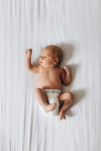 Linda menina recém-nascida deitada na cama, olhar pouco humano ao redor com grande interesse, conhecer um mundo, conceito de nascimento e infância — Fotografia de Stock