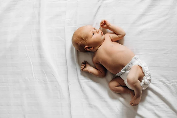 Счастливая новорожденная девочка, лежащая на кровати, маленький человеческий взгляд вокруг с большим интересом, знакомство с миром, рождением и детством — стоковое фото
