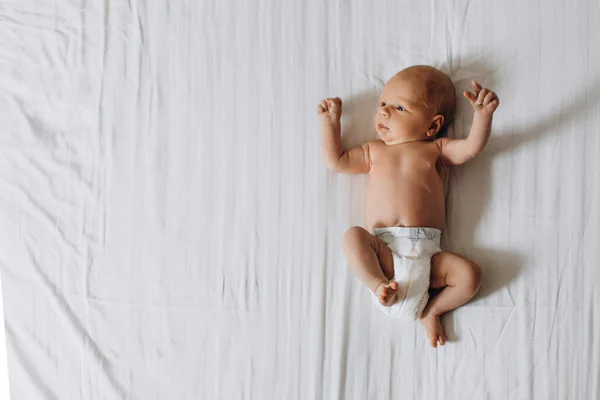 Menina recém-nascido adorável deitado na cama, olhar humano pequeno bonito ao redor com grande interesse, momentos familiares felizes, conceito de nascimento e paternidade — Fotografia de Stock