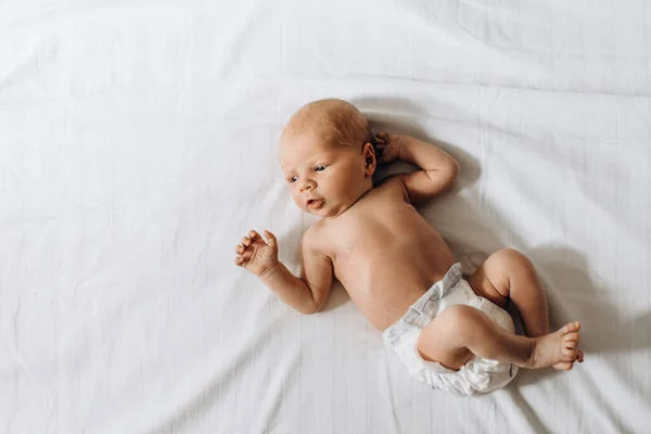Menina recém-nascido adorável deitado na cama, olhar humano pequeno bonito ao redor com grande interesse, momentos familiares felizes, conceito de nascimento e paternidade — Fotografia de Stock