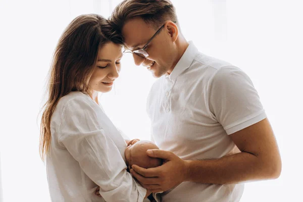 Mooie ouders met pasgeboren baby, liefdevolle moeder houden kleine dochter in de armen, zorgzame vader zachtjes aanraken een hoofd van schattige baby meisje, genieten van tedere momenten, ouderschap concept — Stockfoto