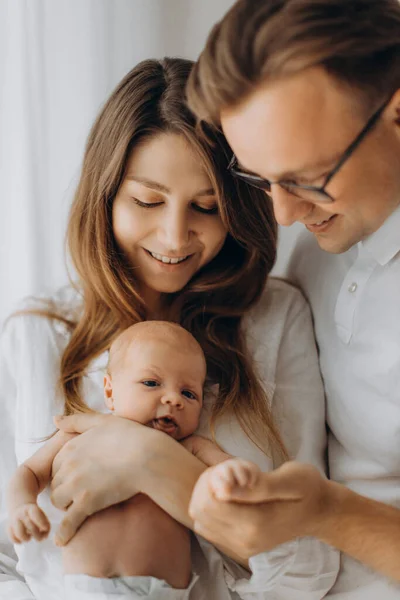 Padres felices con bebé recién nacido, madre cariñosa sostiene a la pequeña hija en brazos, hermoso padre sujeta suavemente la mano de la niña, sonriendo, disfruta de momentos felices, concepto de familia joven — Foto de Stock