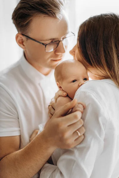 Mooie ouders met pasgeboren baby, liefdevolle moeder houden kleine dochter in de armen, zorgzame vader zachtjes vasthouden van een hand van schattige baby meisje, genieten van tedere familie momenten, ouderschap concept — Stockfoto