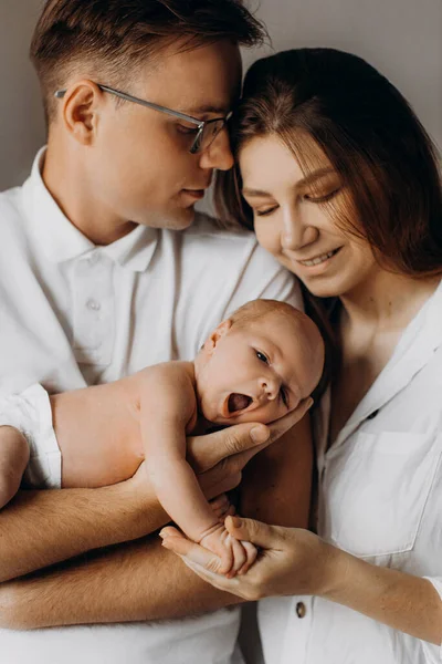 Caring parents with newborn baby, loving dad gently hold little daughter in arms, beautiful mother hold tiny hand of baby girl, smiling, enjoy happy moments, young family concept — Stock Photo, Image