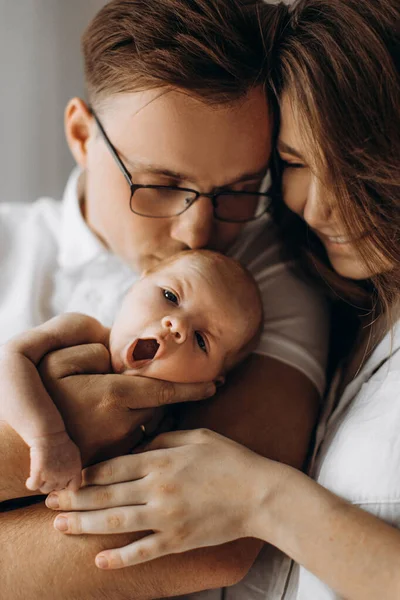 Orang tua yang peduli dengan bayi yang baru lahir, ayah yang penuh kasih dengan lembut memeluk anak perempuan, ibu yang cantik memegang tangan mungil bayi perempuan, tersenyum, menikmati saat-saat bahagia, konsep keluarga muda — Stok Foto