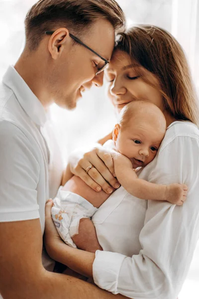 Krásné rodiče s novorozeneckou holčičkou, milující maminka držet malou dceru v náručí, starostlivý manžel jemně objímat rozkošnou manželku, usmívat se, vychutnat něžné rodinné chvíle, rodičovská koncepce — Stock fotografie