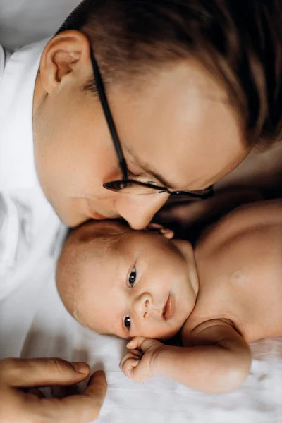 Любимая новорожденная девочка, лежащая на кровати, заботливый папа держит крошечную руку маленькой дочки, нежные моменты прощания, улыбка, понятие отцовства — стоковое фото