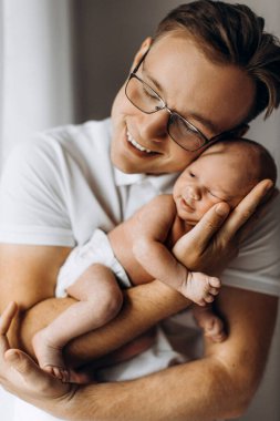Sevgi dolu bir baba, yeni doğmuş bir kız bebek, sevgi dolu bir baba kucağında güzel bir kız çocuğu, şefkatli ebeveyn anları, gülümseme, babalık ve çocukluk kavramının keyfini çıkar.