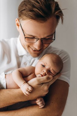 Sevgi dolu bir baba, yeni doğmuş bir kız bebek, sevgi dolu bir baba kucağında güzel bir kız çocuğu, şefkatli ebeveyn anları, gülümseme, babalık ve çocukluk kavramının keyfini çıkar.