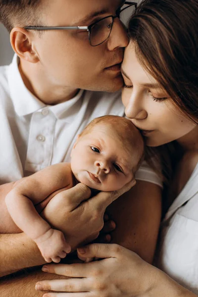 Gelukkige ouders met schattige pasgeboren baby, liefhebbende vader houden kleine dochter in de armen, zorgzame moeder kussen mooie baby meisje, jong gezin brengen tijd samen, ouderschap concept — Stockfoto