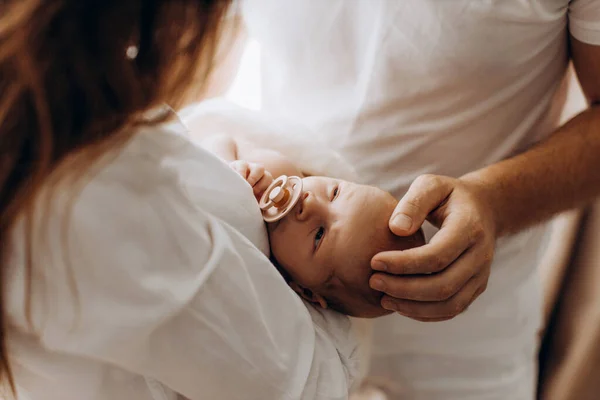 Mooie ouders met pasgeboren baby, liefdevolle moeder houden kleine dochter in de armen, zorgzame vader zachtjes aanraken een hoofd van schattige baby meisje, genieten van tedere momenten, ouderschap concept — Stockfoto