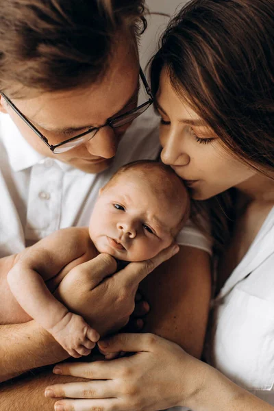 Happy parents with cute newborn baby girl, handsome dad hold little daughter in arms, beautiful wife and loving husband gently kiss their child, young family concept — Stock fotografie