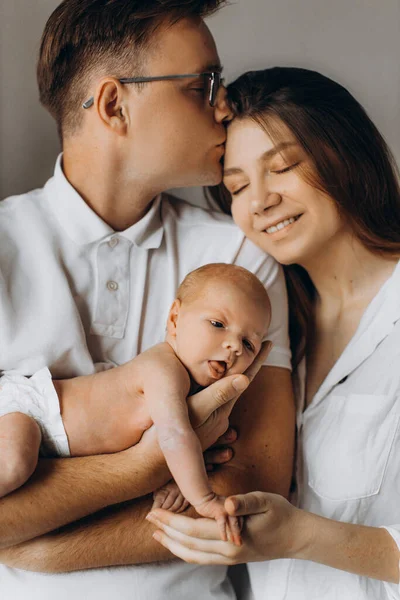 Szczęśliwi rodzice z noworodka dziewczynka, kochający tata trzymać małą córeczkę w ramionach, opiekuńczy mąż pocałować wspaniałą żonę, cieszyć się szczęśliwe chwile, młoda koncepcja rodziny — Zdjęcie stockowe
