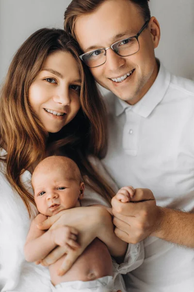 Retrato de los padres con el bebé recién nacido, madre cariñosa suavemente sostener a la pequeña hija en brazos, padre cariñoso sostener la pequeña mano de la niña, sonriendo, disfrutar de momentos felices, concepto de familia joven — Foto de Stock