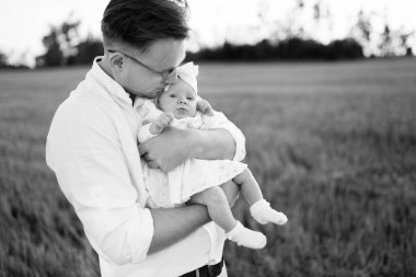 Tarlada sevimli bir kızı olan yakışıklı bir baba, şefkatli bir baba yeni doğmuş tatlı bir bebeği kollarına alıyor, hassas aile anları, ebeveynlik ve babalık kavramları. 