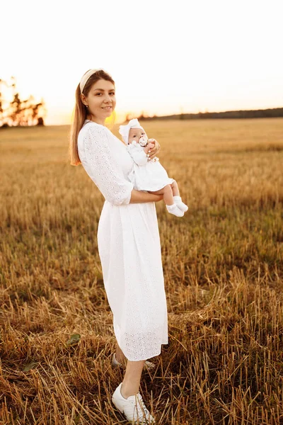 Mãe maravilhosa com linda filhinha andando no campo, mãe elegante segurar bonito bebê recém-nascido menina nos braços, momentos familiares felizes, parentalidade e conceito de maternidade — Fotografia de Stock